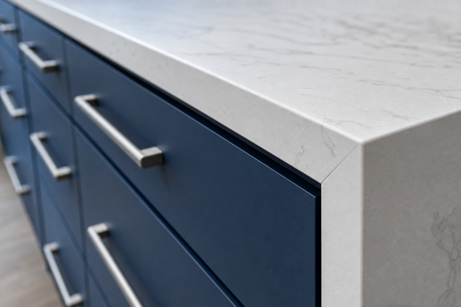 Close-up of aligned cabinet drawers, brushed steel pulls and a mitred quartz countertop edge in a Calgary kitchen